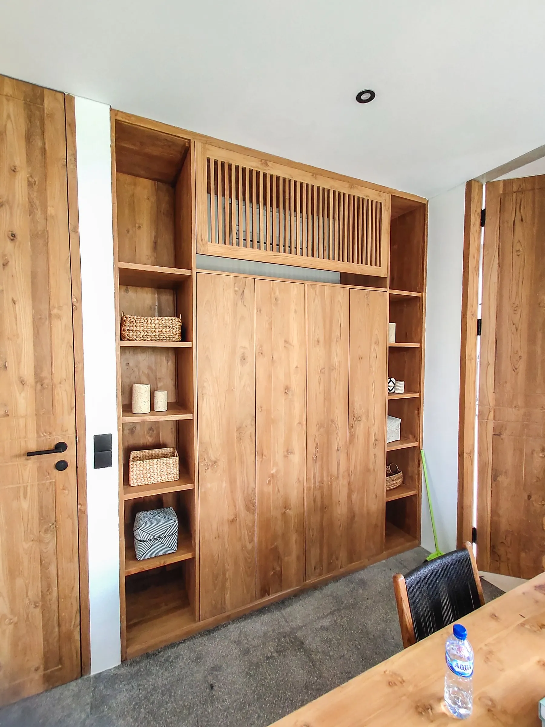 Built-in teak wardrobe with a slatted top section and open shelving.