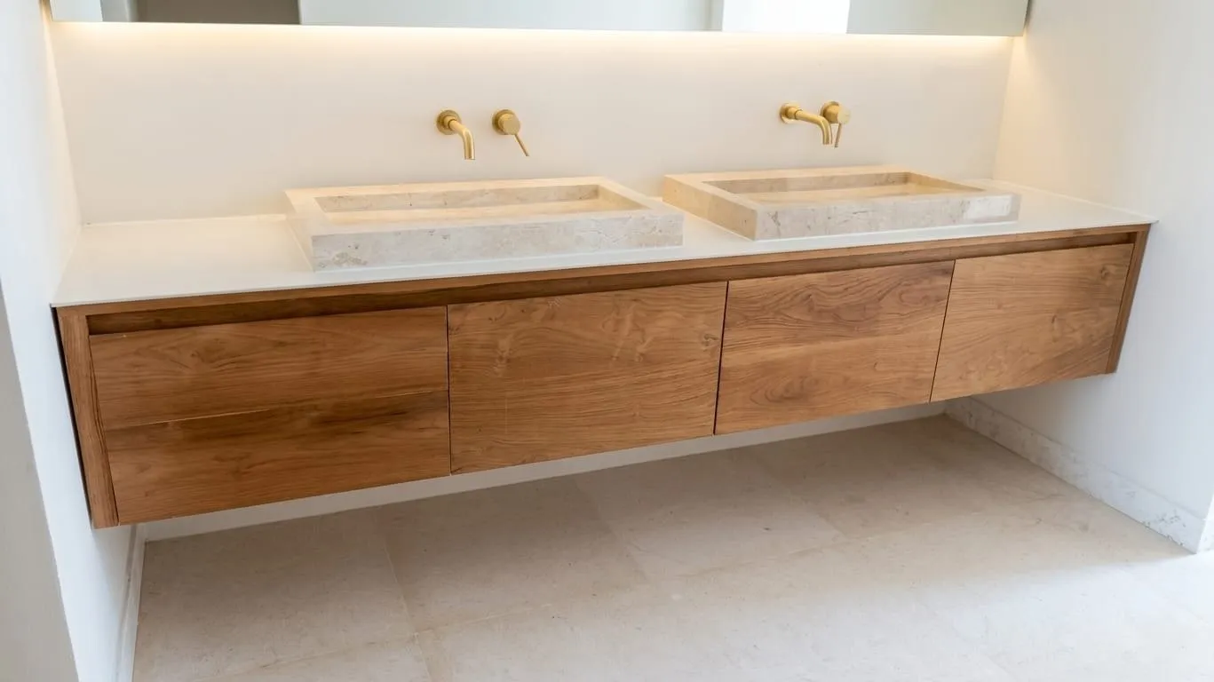 Floating teak vanity with twin stone basins and brass taps.