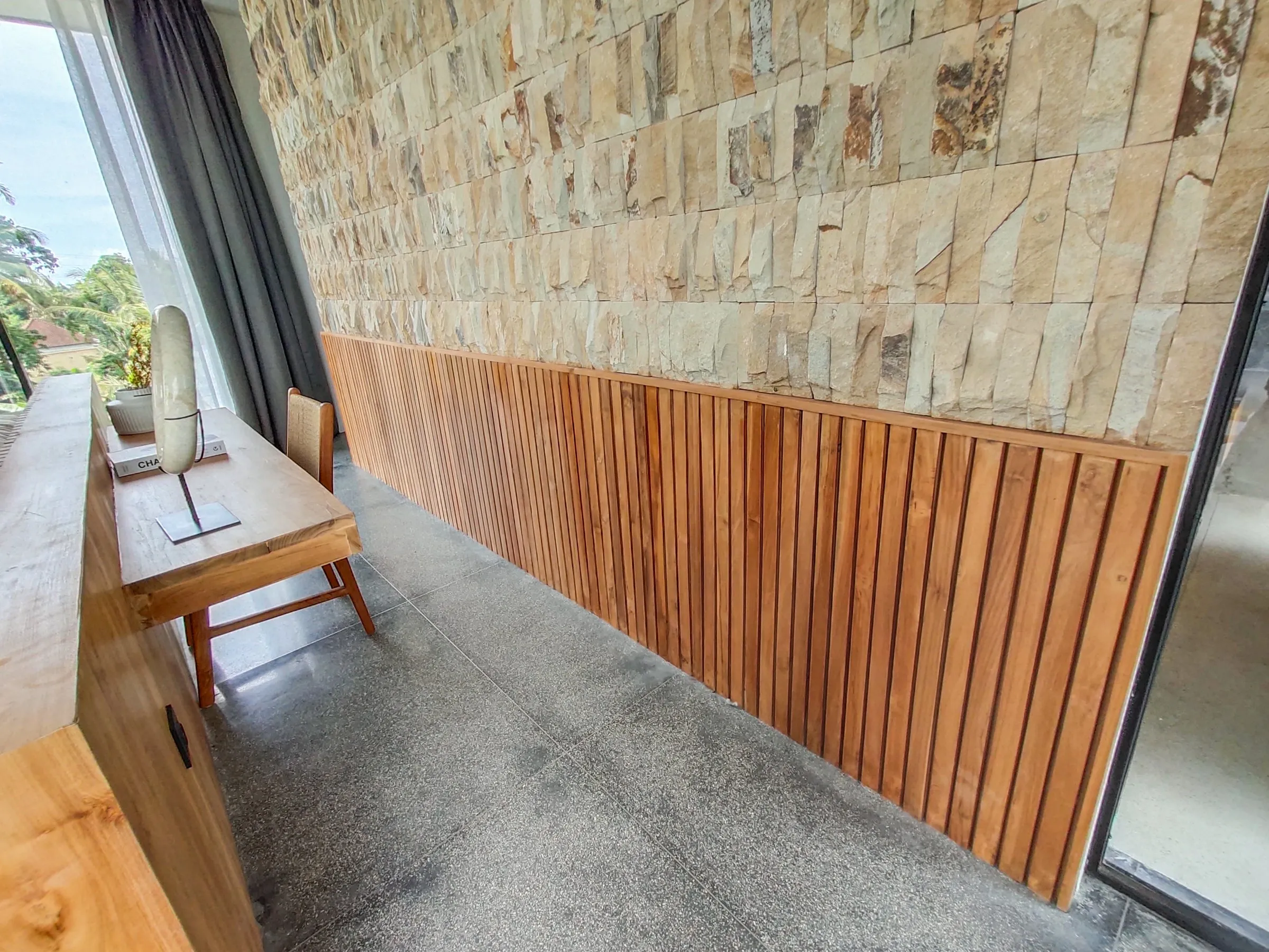 Slatted teak panelling along a stone wall.