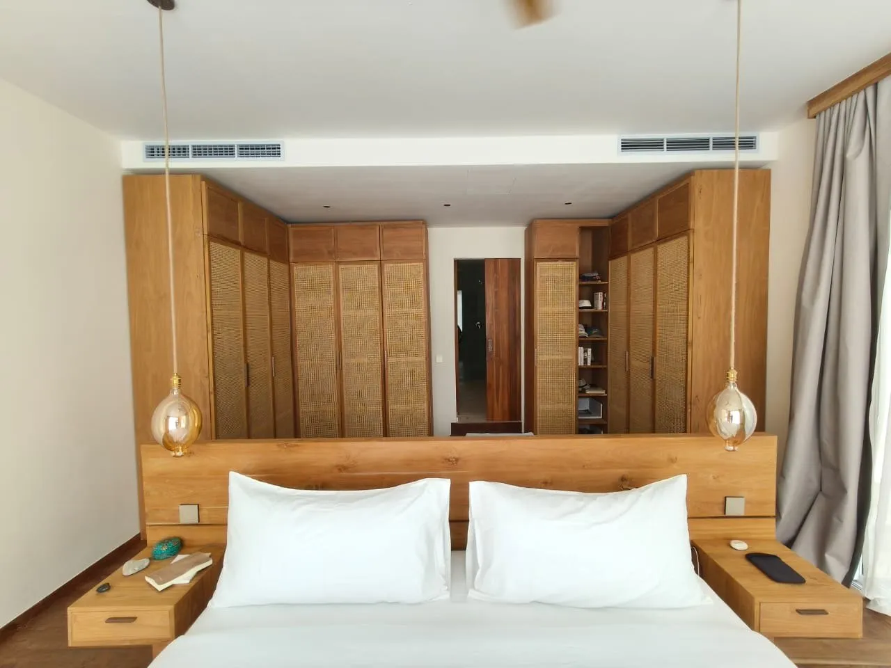 Teak headboard wall with integrated bedside units, framed by wardrobes.