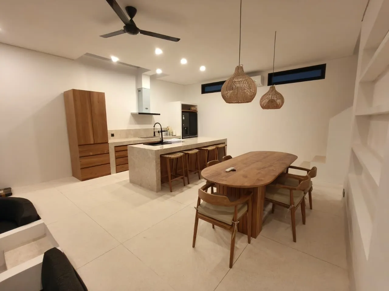 Open-plan kitchen with teak joinery and an oval teak dining table.