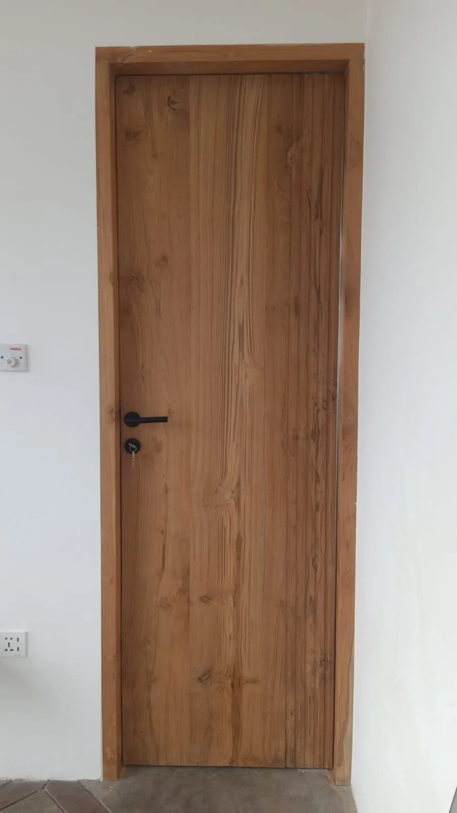 Solid teak door with dark handle.